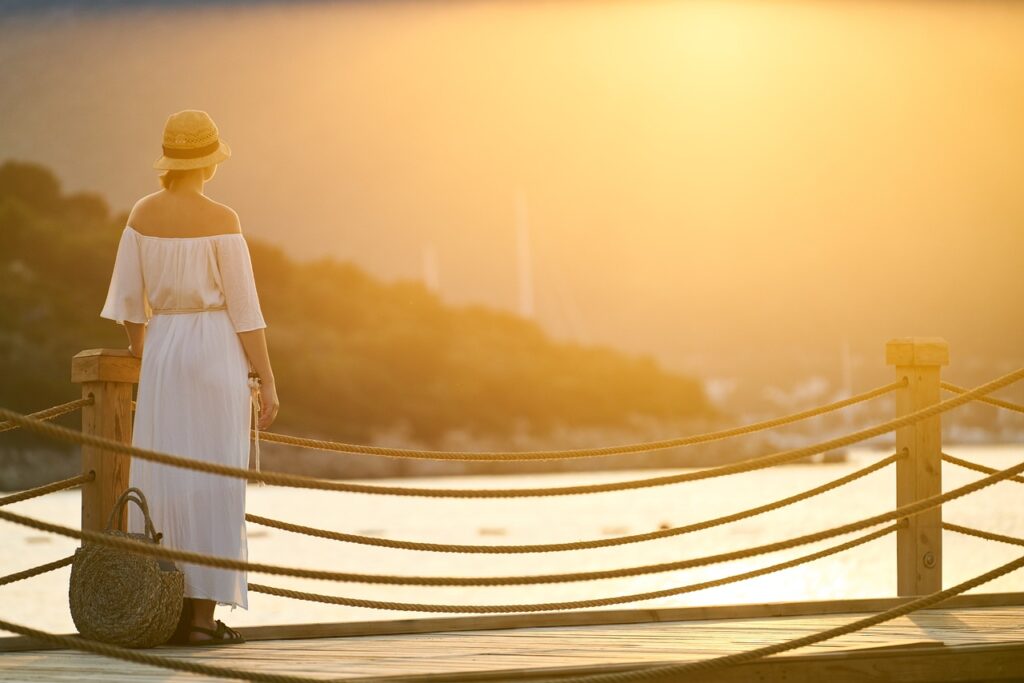 Woman standing at a dock in golden morning light