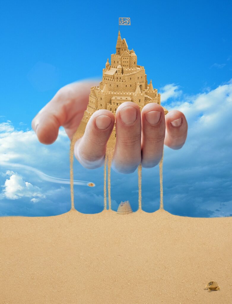 giant hand holding a sand castle
