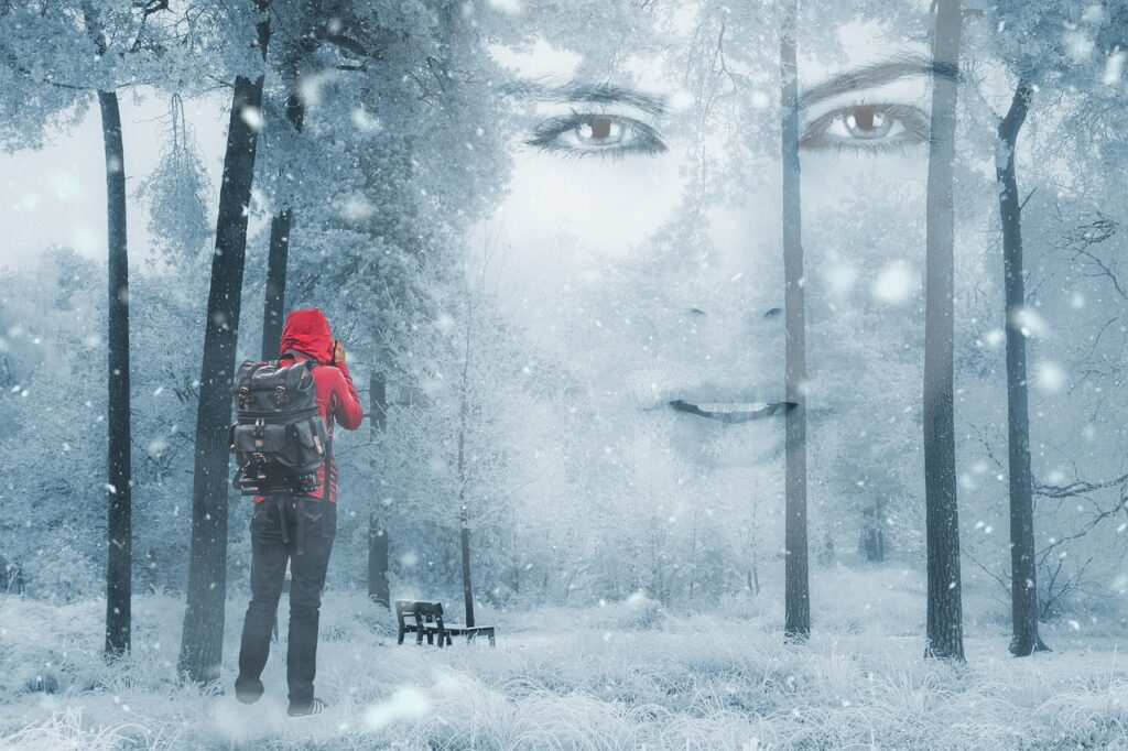 Photographer in the snow in a wintry park with a large woman's face peering between the trees